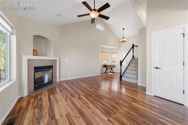 unfurnished living room with hardwood / wood-style floors, a tile fireplace, and ceiling fan