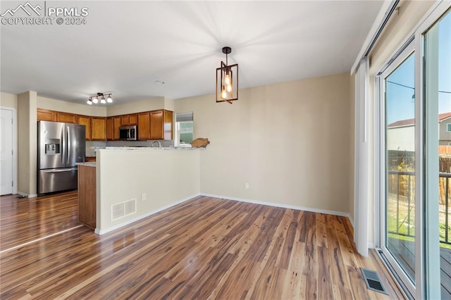 kitchen with a healthy amount of sunlight, stainless steel appliances, decorative light fixtures, and kitchen peninsula