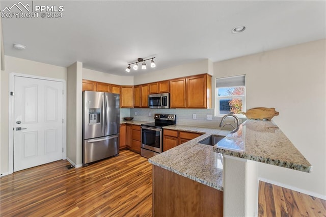 kitchen with light stone countertops, sink, appliances with stainless steel finishes, and kitchen peninsula