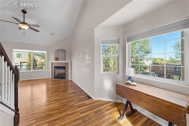 interior space featuring vaulted ceiling, hardwood / wood-style flooring, a tile fireplace, and ceiling fan