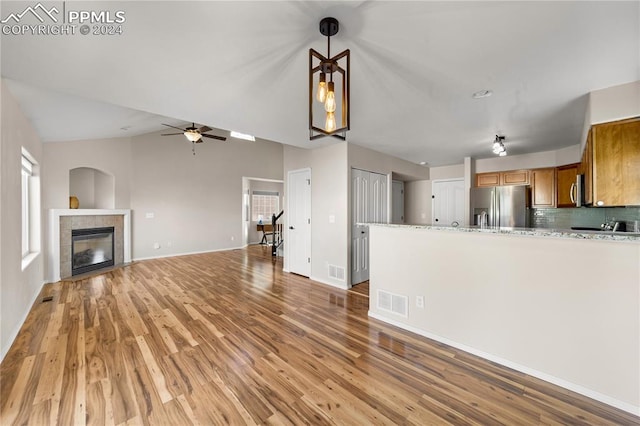 kitchen with light stone countertops, appliances with stainless steel finishes, hardwood / wood-style floors, ceiling fan, and vaulted ceiling