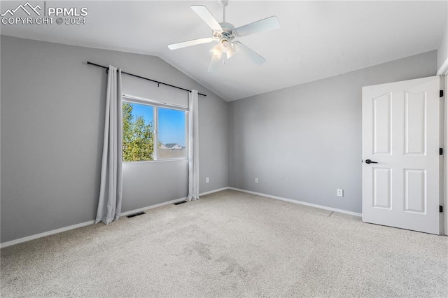 spare room with ceiling fan, light colored carpet, and vaulted ceiling