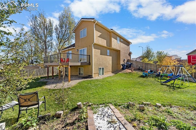 rear view of property featuring a yard, a deck, and a playground