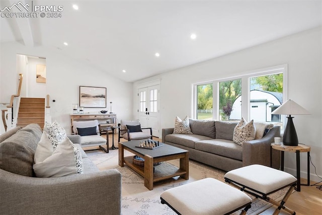 living room featuring french doors, vaulted ceiling, and light wood-type flooring