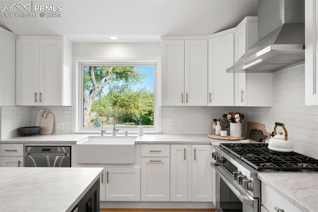 kitchen with sink, wall chimney exhaust hood, stainless steel appliances, and white cabinetry