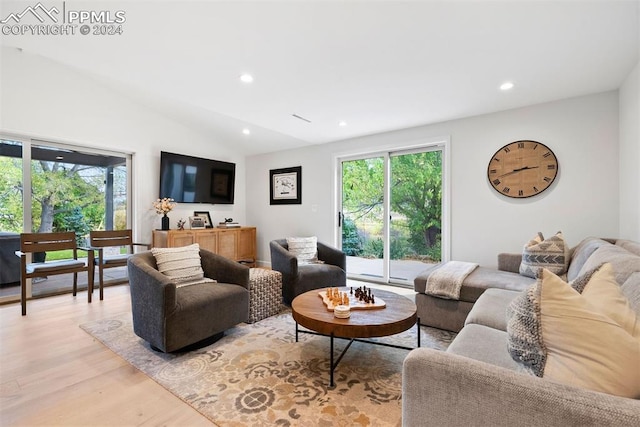 living room with lofted ceiling, light wood-type flooring, and a wealth of natural light