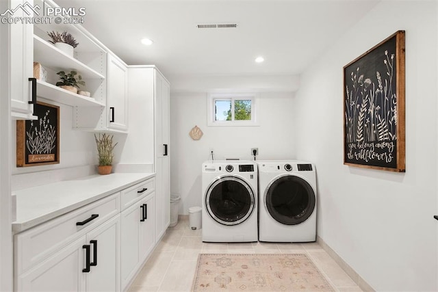 laundry room featuring cabinets, light tile patterned floors, and washing machine and clothes dryer