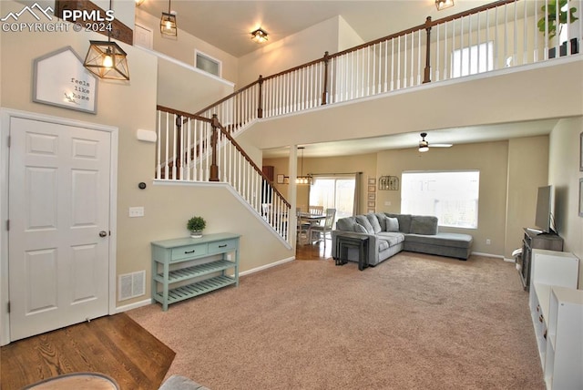 living room with ceiling fan, a towering ceiling, and carpet