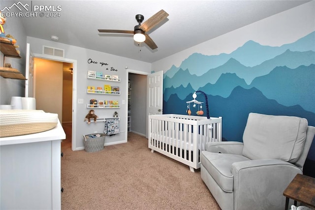 carpeted bedroom with a nursery area and ceiling fan