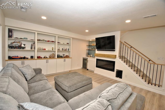 living room featuring beverage cooler, light hardwood / wood-style floors, and a textured ceiling