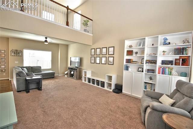 living room featuring ceiling fan, carpet flooring, and a high ceiling