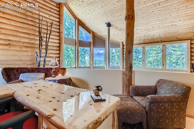 sitting room with wood ceiling, high vaulted ceiling, plenty of natural light, and rustic walls