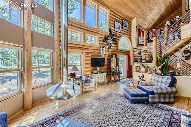 living room with high vaulted ceiling, hardwood / wood-style flooring, a healthy amount of sunlight, and wooden ceiling