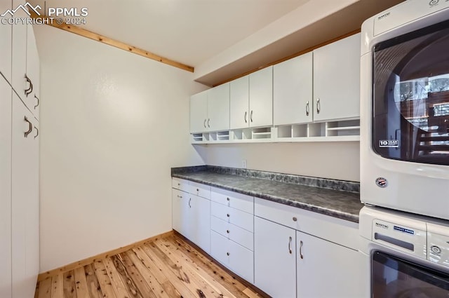 9 Arapahoe St, Woodland Park, CO 80863 - kitchen featuring estacked washer and dryer, dark countertops, light wood-style flooring, white cabinets, and baseboards