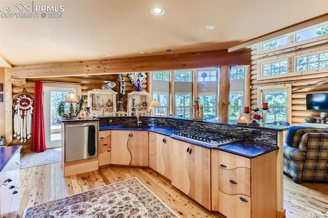 kitchen featuring plenty of natural light, log walls, light brown cabinetry, and light wood-type flooring