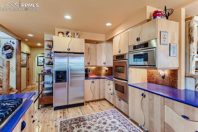 kitchen featuring tasteful backsplash, stainless steel appliances, and light wood-type flooring