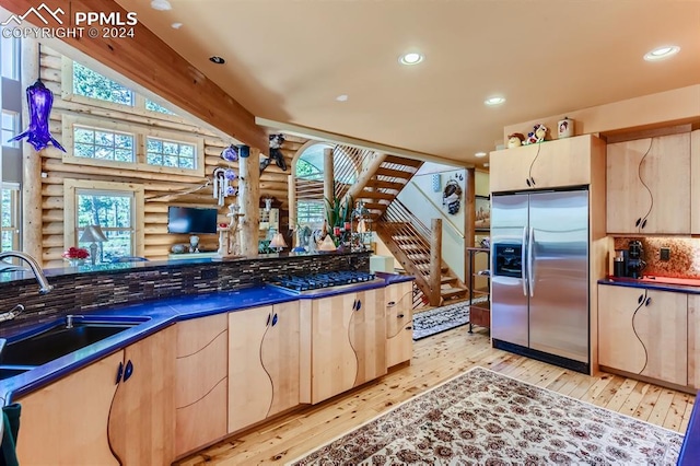 kitchen with log walls, sink, appliances with stainless steel finishes, and light hardwood / wood-style floors