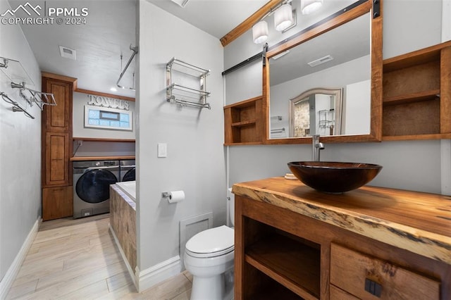 bathroom with toilet, vanity, wood-type flooring, and washing machine and dryer