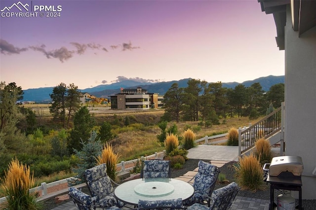 patio terrace at dusk featuring a mountain view and grilling area