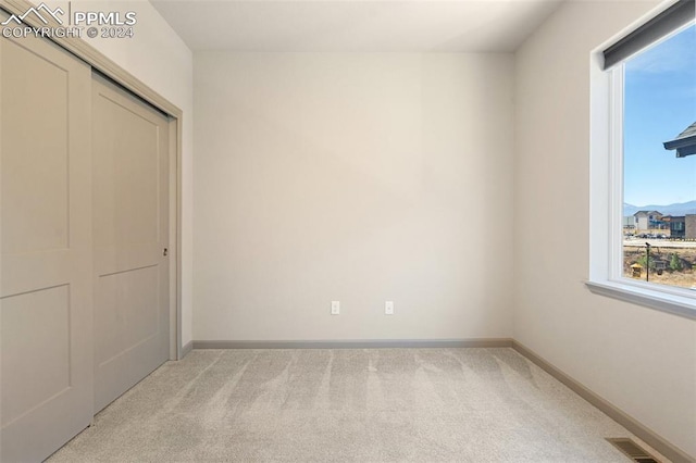 unfurnished bedroom with light carpet and a closet