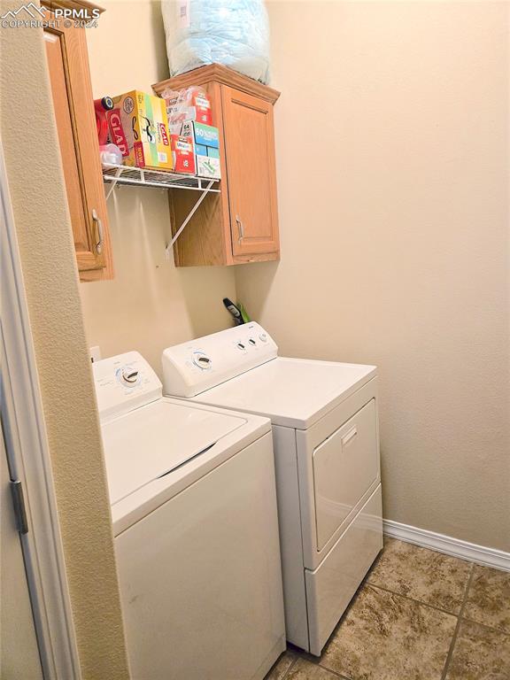 washroom with light tile patterned flooring, cabinets, and separate washer and dryer