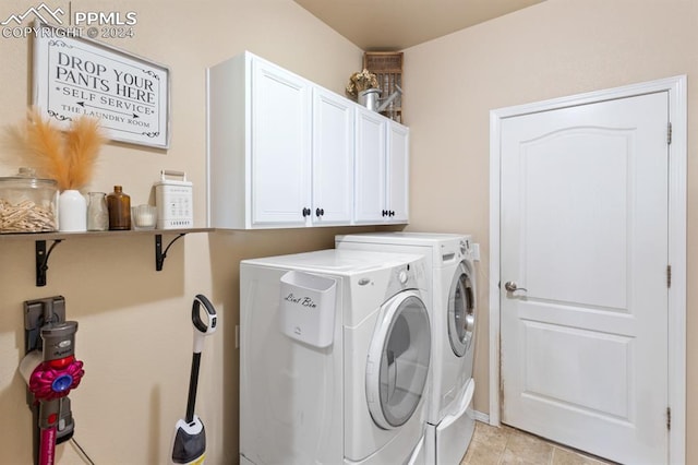 laundry room with cabinets, light tile patterned floors, and washing machine and dryer