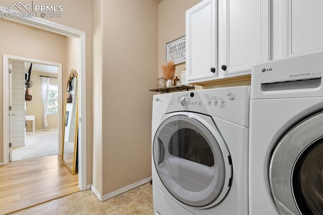 washroom featuring cabinets, light wood-type flooring, and washing machine and dryer