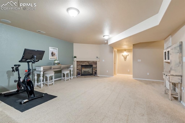 exercise room with light carpet and a stone fireplace