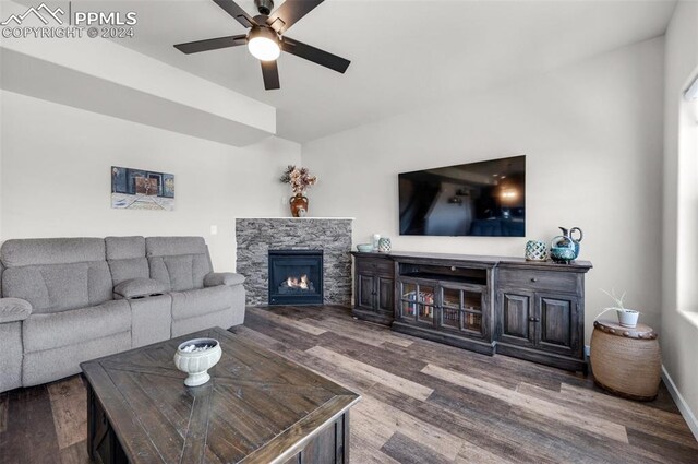 living room featuring a stone fireplace, hardwood / wood-style floors, and ceiling fan