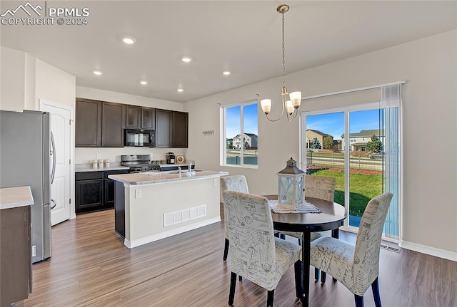 kitchen with hanging light fixtures, wood-type flooring, black appliances, dark brown cabinetry, and sink