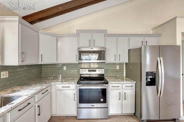 kitchen with light stone counters, stainless steel appliances, backsplash, white cabinets, and lofted ceiling