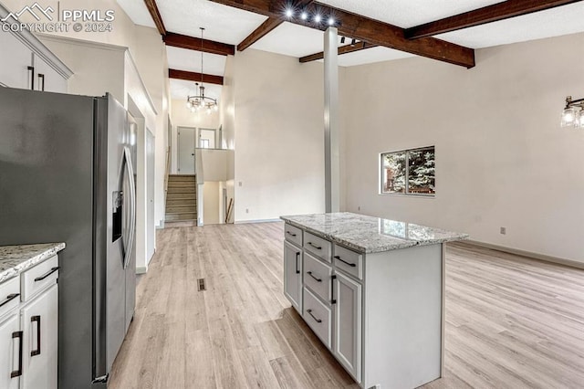 kitchen featuring light hardwood / wood-style floors, stainless steel refrigerator with ice dispenser, a kitchen island, and beam ceiling