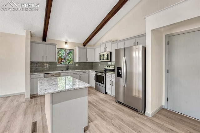 kitchen featuring tasteful backsplash, light hardwood / wood-style flooring, appliances with stainless steel finishes, lofted ceiling with beams, and a center island