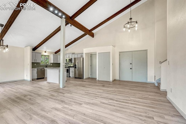 unfurnished living room with an inviting chandelier, light wood-type flooring, and high vaulted ceiling