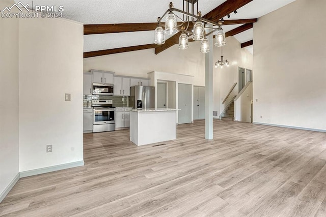 kitchen featuring a center island, stainless steel appliances, hanging light fixtures, light hardwood / wood-style flooring, and a textured ceiling