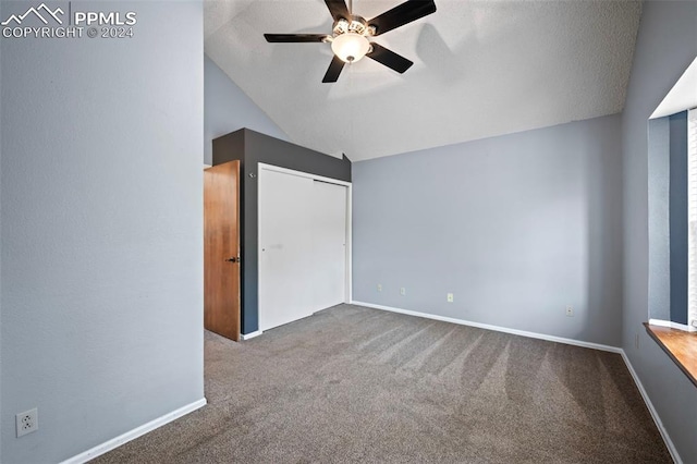 unfurnished bedroom featuring lofted ceiling, carpet, ceiling fan, a textured ceiling, and a closet