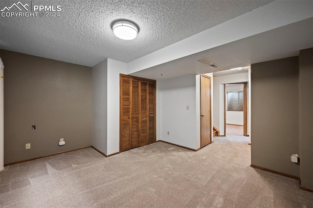 interior space featuring light carpet, a textured ceiling, and a closet