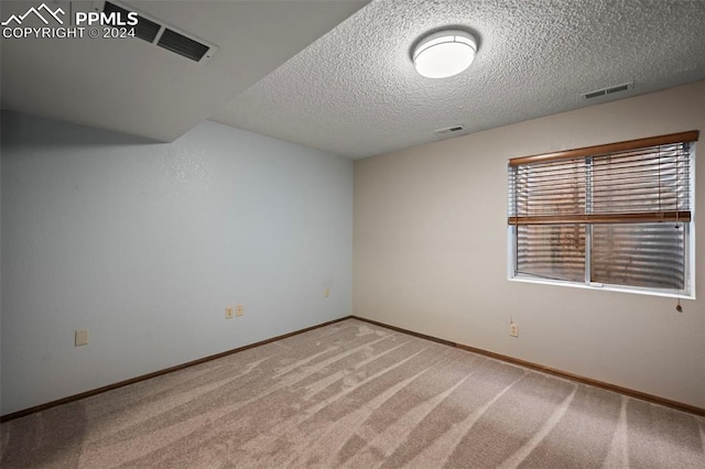 carpeted empty room with a textured ceiling