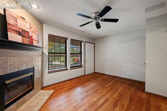 unfurnished living room with ceiling fan, a textured ceiling, a fireplace, and hardwood / wood-style floors