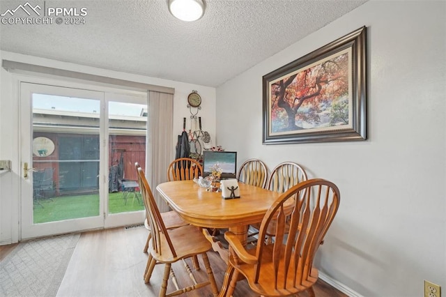 dining space with wood-type flooring and a textured ceiling