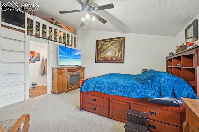 carpeted bedroom featuring ceiling fan, lofted ceiling, and a textured ceiling