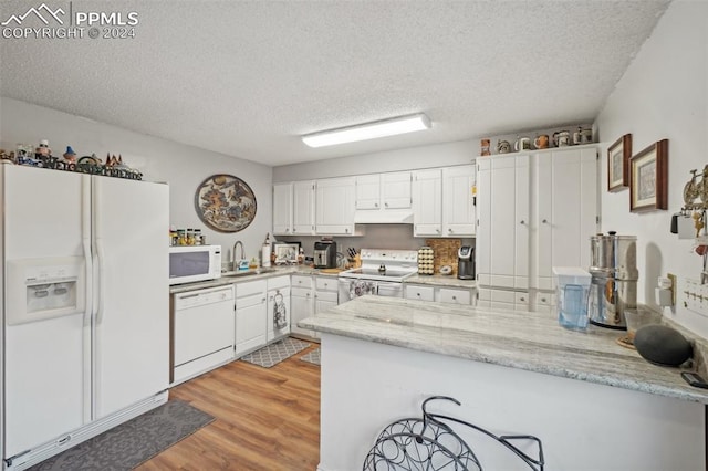 kitchen with sink, light hardwood / wood-style flooring, kitchen peninsula, white appliances, and white cabinets