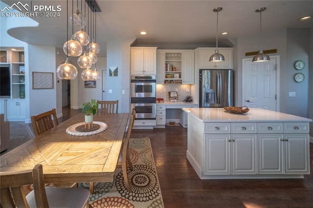 kitchen featuring white cabinets, appliances with stainless steel finishes, hanging light fixtures, and a kitchen island