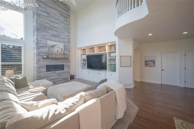 living room with a high ceiling, dark wood-type flooring, and a stone fireplace