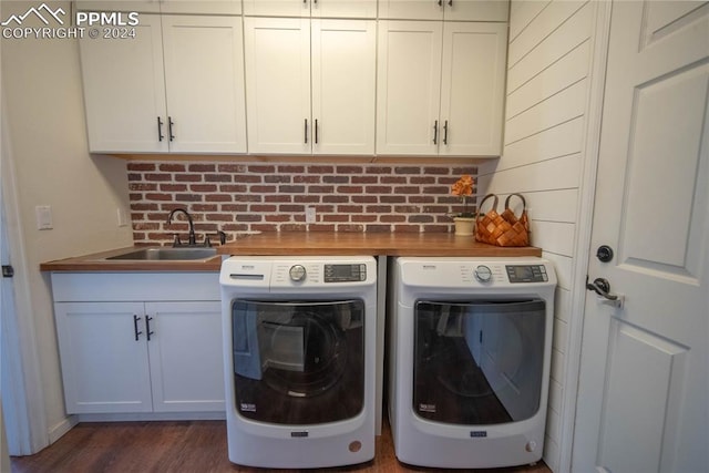 washroom with dark hardwood / wood-style flooring, cabinets, sink, and washing machine and clothes dryer