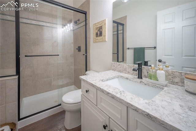 bathroom with hardwood / wood-style flooring, an enclosed shower, vanity, and toilet