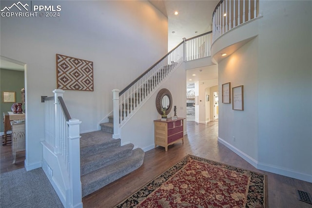 staircase with hardwood / wood-style flooring and a high ceiling