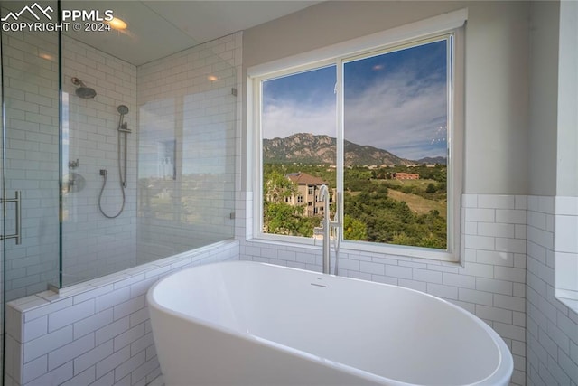 bathroom featuring a mountain view, separate shower and tub, and tile walls