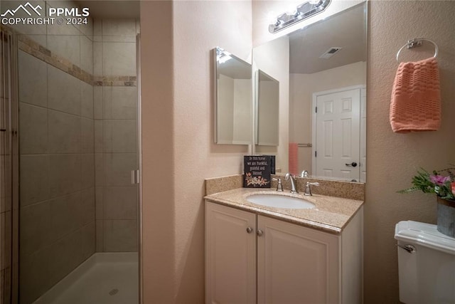 bathroom featuring vanity, toilet, and a shower with shower door