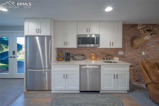 kitchen featuring french doors, stainless steel appliances, white cabinets, sink, and light hardwood / wood-style floors